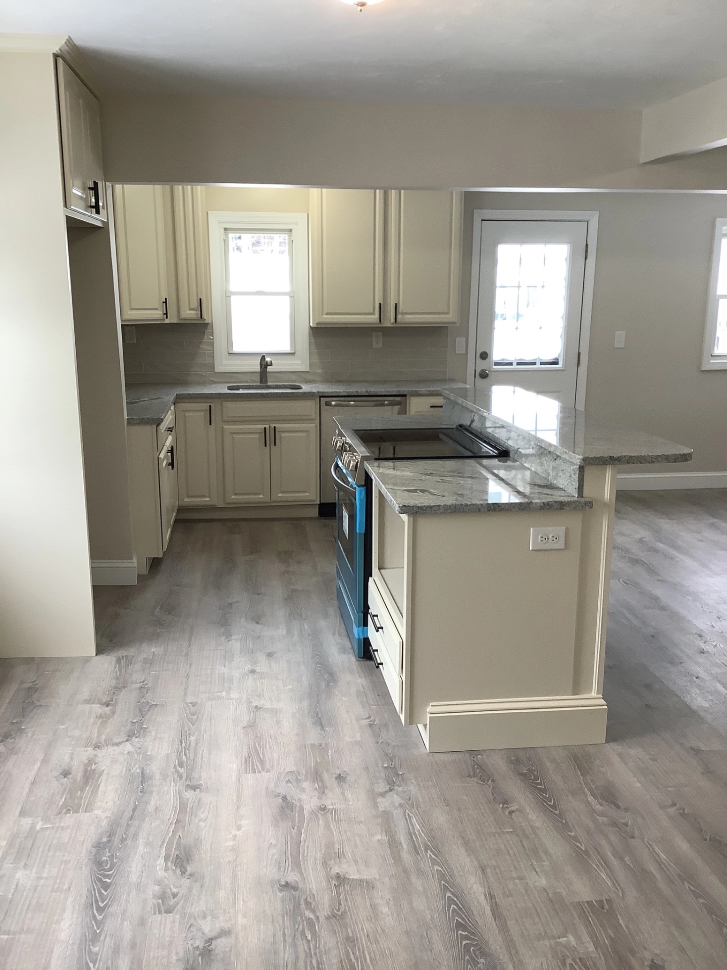 Kitchen with beige cabinets, granite countertop, electric range, undermount sink, and light wood flooring.