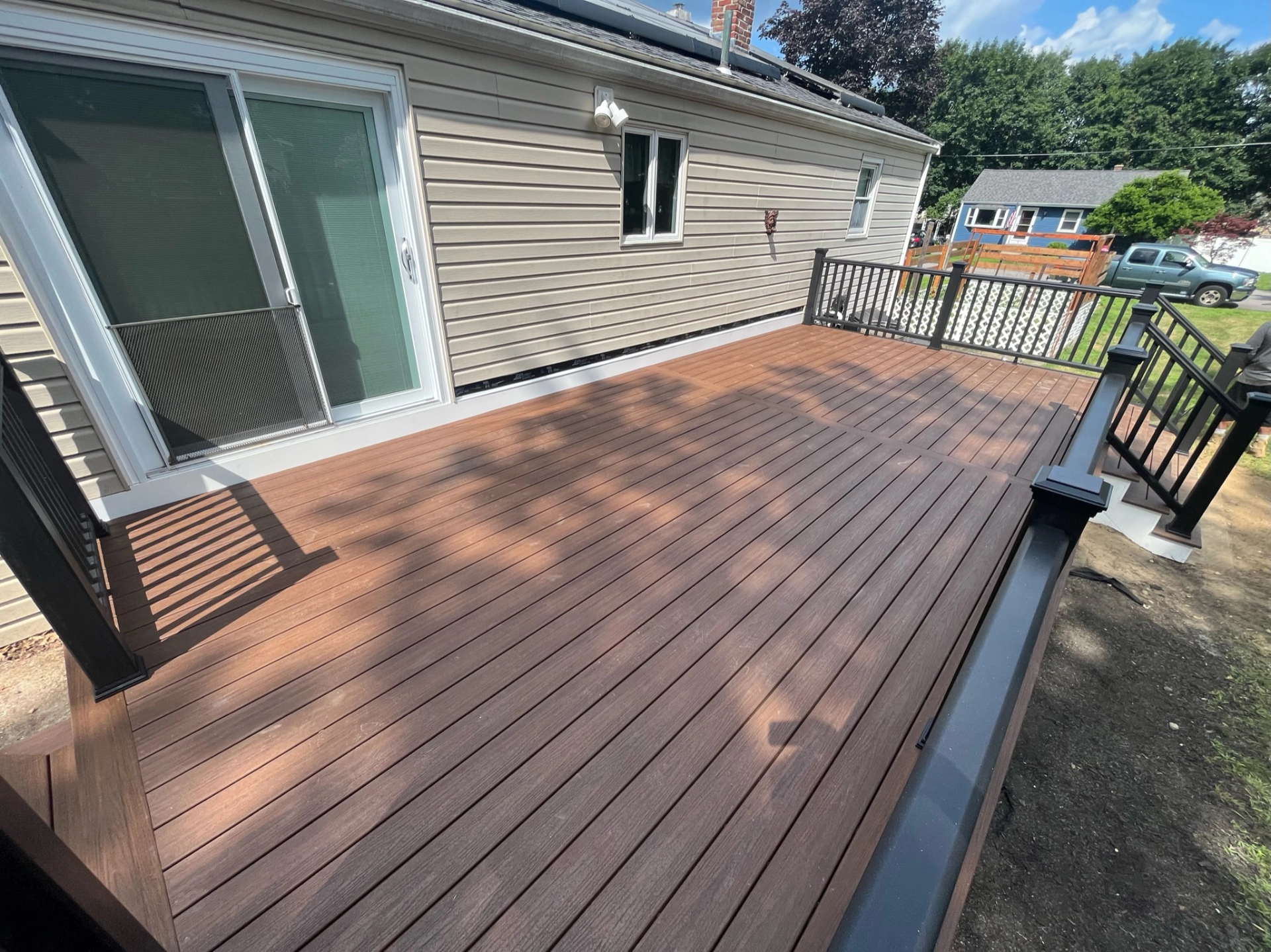 composite-decking-with-black-metal-railing-and-a-sliding-glass-door-in-needham-ma