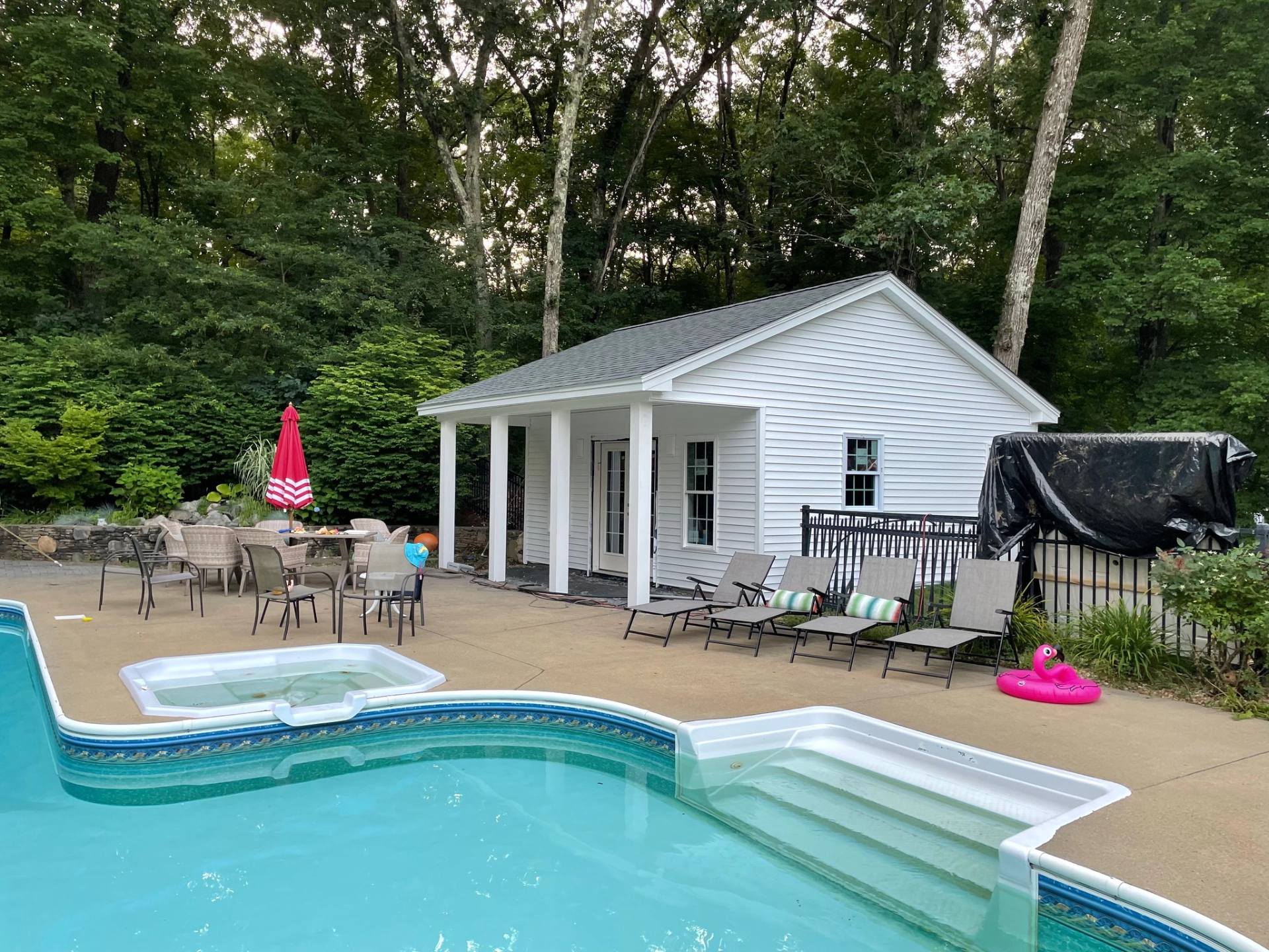 patio-with-outdoor-furniture-and-a-pool-beside-the-white-house-with-black-metal-fence-in-needham-ma
