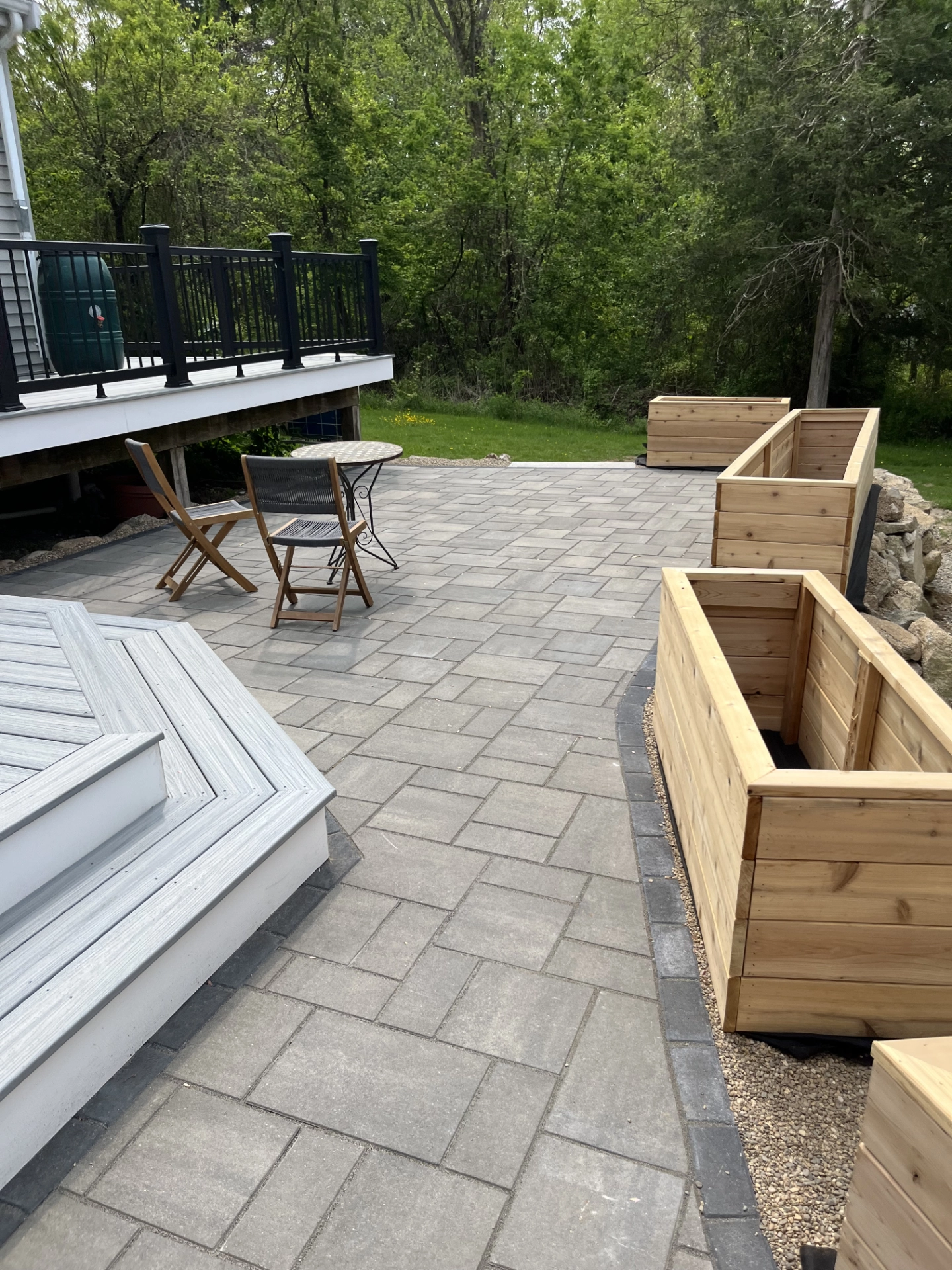 patio-with-wooden-box-and-elevated-deck-with-black-railing-in-needham-ma