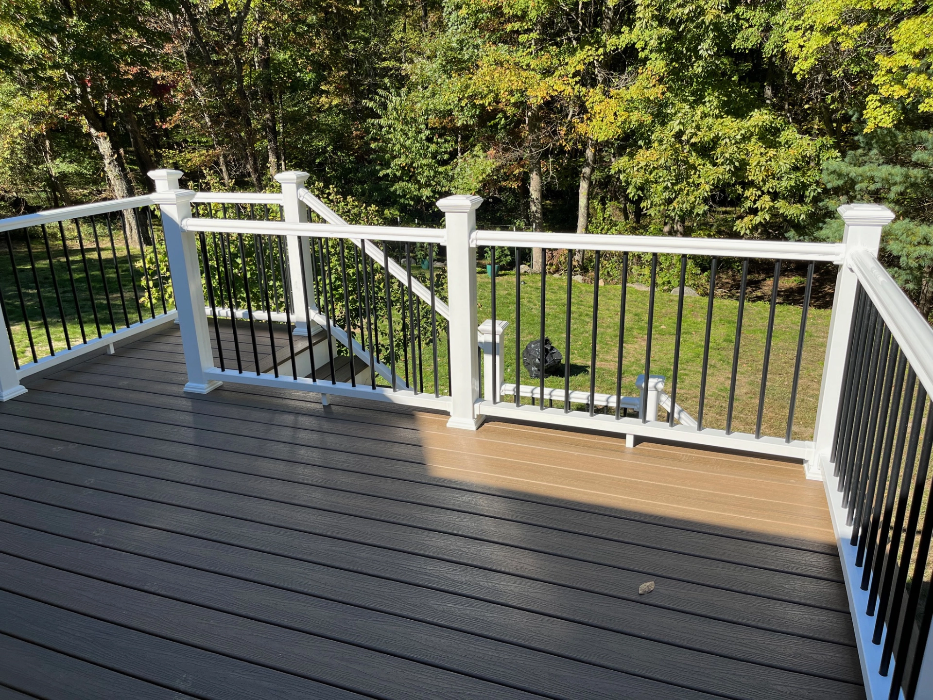 residential-deck-with-white-black-railing-and-surrounded-by-big-trees-in-needham-ma
