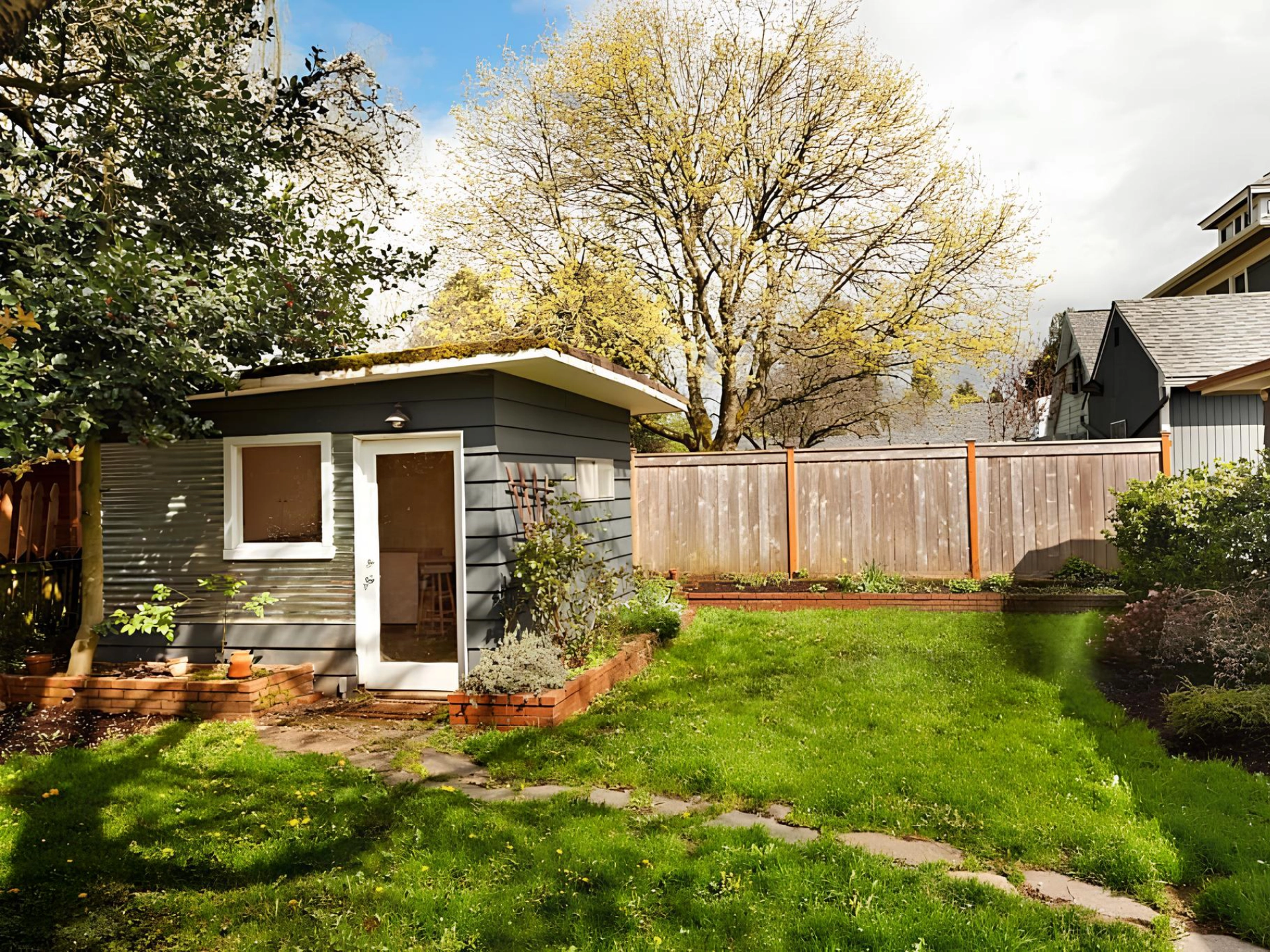 small-gray-shed-with-white-framed-windows-with-wide-wooden-fence-featuring-trees-on-the-background-in-needham-ma