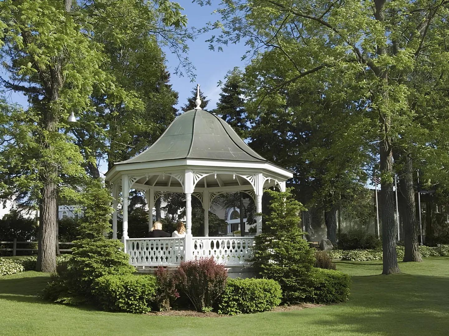 victorian-gazebo-surrounded-by-grass-and-plants-featuring-big-trees-on-the-side-in-needham-ma